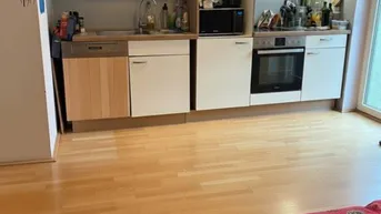 Funktionale Küche mit hellen Schränken, Holzboden und integrierten Geräten.