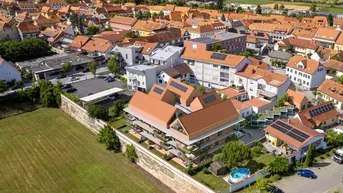 Luftaufnahme eines modernen Wohngebäudes, eingebettet in eine städtische Umgebung mit viel Grün.