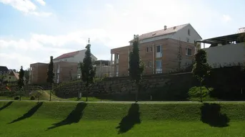 Moderne Neubauten in Hanglage mit weitläufigen Grünflächen und sonnigem Ausblick auf die Umgebung.