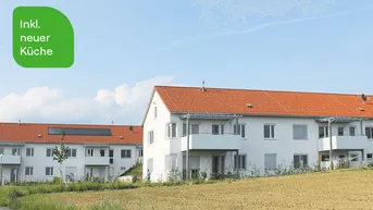 Mehrere moderne Wohngebäude mit roten Ziegeldächern und Balkonen in ländlicher Umgebung.