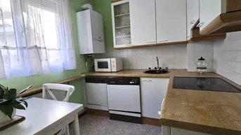 Funktionale Küche mit Holz-Arbeitsplatten, Spüle, Herd und Geschirrspüler.