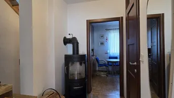 Gemütlicher Flur mit Parkettboden und einem modernen Holzofen als Wärmequelle.