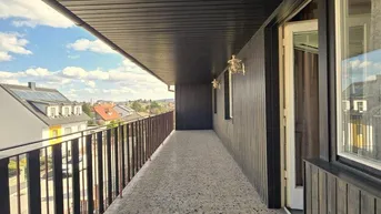 Langer, überdachter Balkon mit Fliesenboden und weitem Blick über die Umgebung.