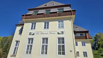 Historisches Gebäude mit gelber Fassade, Mansarddach und dekorativer Schrift.