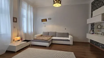 Helles Wohnzimmer mit modernem Sofa, Teppich und dekorativer Wandgestaltung.