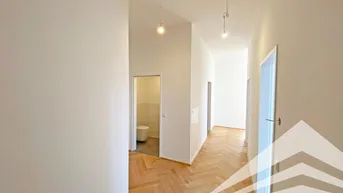 Heller Flur mit Fischgrätparkettboden und Zugang zu einem Gäste-WC.