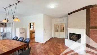 Gemütlicher Essbereich mit Holztisch, Terrakottafliesen, modernem Kamin und rustikalen Holzbalken.
