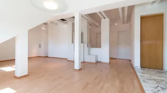 Helles, offenes Dachgeschosszimmer mit Holzbalken, Kachelofen und Parkettboden.