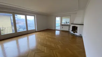Helles Wohnzimmer mit Fischgrätparkett, Kamin und Zugang zu zwei Balkonen.