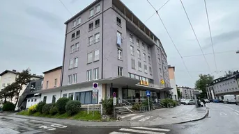Gebäude an einer Straßenecke mit moderner Architektur und großen Fenstern im Stadtgebiet.