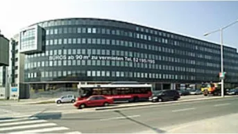 Großes Bürogebäude mit moderner, dunkler Fassade und vielen Fenstern an einer belebten Straße.