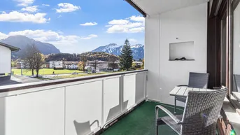 Sonniger Balkon mit Sitzgelegenheiten und weitem Blick auf die umliegende Berglandschaft.