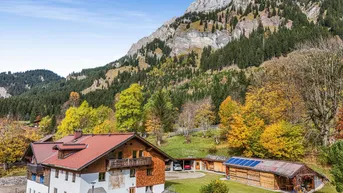 Traditionelles Haus mit Holzbalkonen und einem beeindruckenden Bergpanorama im Hintergrund.