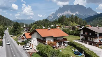 Luftaufnahme eines Hauses in alpiner Umgebung mit Bergblick und Garten.