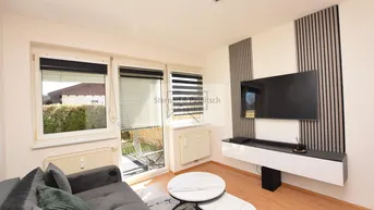 Helles Wohnzimmer mit modernem TV-Möbel, Holzboden und Zugang zur Terrasse.