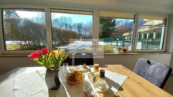 Helles Esszimmer mit Holztisch und Blick ins Grüne, ideal für gemütliche Mahlzeiten.