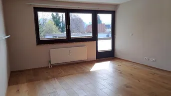 Heller Raum mit Holzboden, großen Fenstern und Zugang zu einem Außenbereich.