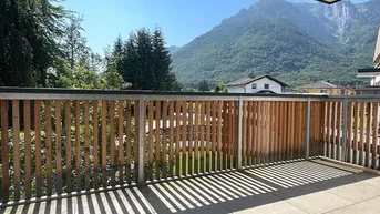 Geräumiger Balkon mit Holzelementen und herrlichem Bergblick unter blauem Himmel.