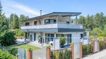 Modernes Einfamilienhaus mit mehreren Balkonen, Garten und umzäuntem Grundstück.