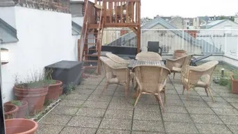 Geräumige Dachterrasse mit Sitzgelegenheiten aus Rattan und einem kleinen Spielturm.
