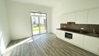 Heller offener Wohnbereich mit integrierter Küche, Holzboden und Zugang zum Garten.