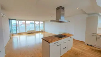 Heller offener Wohnbereich mit Holzboden, integrierter Küche und großen Fenstern mit Stadtblick.