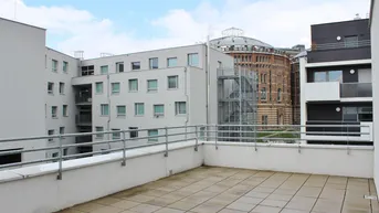 Geräumige Terrasse mit Fliesenboden und Blick auf moderne Gebäude sowie historische Architektur.