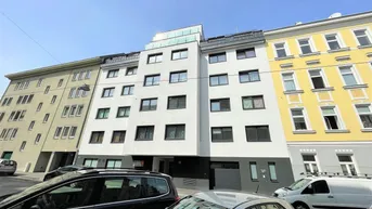 Modernes Mehrfamilienhaus mit weißer Fassade, umgeben von älteren Gebäuden in einer städtischen Umgebung.