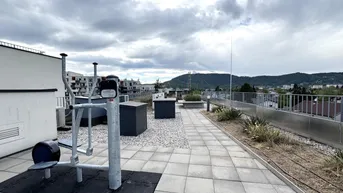 Dachterrasse mit Outdoor-Fitnessgeräten und weitem Blick über die Stadt und Hügel.