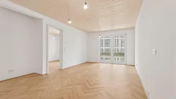 Helles Wohnzimmer mit Fischgrätparkettboden, Holzbalkendecke und Zugang zu einem Balkon.