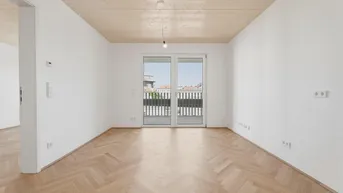 Helles Zimmer mit Fischgrätparkettboden und Zugang zu einem Balkon, ideal als Wohn- oder Schlafzimmer.