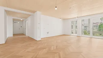 Heller, leerer Raum mit Fischgrätparkett, Holzbalkendecke und Zugang zu einem Balkon.