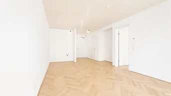 Helles, unmöbliertes Wohnzimmer mit Fischgrätparkett und Holzdeckenverkleidung, bereit zur individuellen Gestaltung.