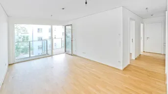Helles Wohnzimmer mit Parkettboden und Zugang zu einem Balkon in einem Neubau.