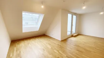 Helles Zimmer im Dachgeschoss mit Holzboden, Dachfenster und Zugang zu einem Außenbereich.