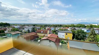 Geräumiger Balkon mit Glasbrüstung und weitem Blick über die Stadt und die grüne Umgebung.
