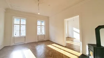 Helles Wohnzimmer mit Fischgrätparkett, Stuckdecke und einem modernen Kaminofen.
