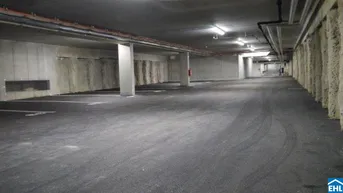 Geräumige und gut beleuchtete Tiefgarage mit markierten Stellplätzen in einem modernen Gebäude.