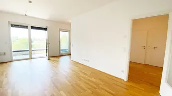 Helles Wohnzimmer mit Parkettboden, weißen Wänden und Zugang zu einem Balkon.