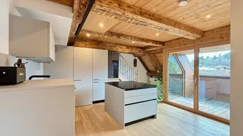 Moderne Küche mit Kochinsel, Holzbalken und Zugang zu einer Dachterrasse.