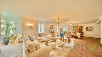 Großzügiger Wohnbereich mit eleganten Sofas, Kunstwerken und Blick in den Essbereich.