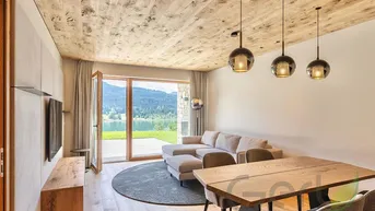 Heller Wohn- und Essbereich mit Holzboden, Holzbalkendecke und Blick auf den See.