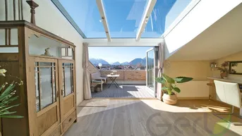Lichtdurchfluteter Wintergarten mit Glasdach und Zugang zur Dachterrasse, bietet einen herrlichen Bergblick.