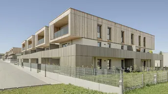 Moderne Wohngebäude mit Holzfassade und Balkonen in einer Reihenhausanlage.