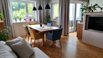 Heller Wohn- und Essbereich mit Holzboden, modernen Möbeln und Zugang zum Balkon.
