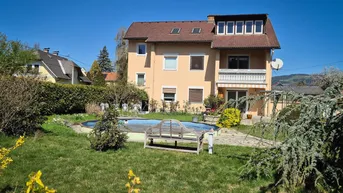 Gepflegter Garten mit Rasenfläche, kleinem Pool und einer Holzbank vor dem Haus.