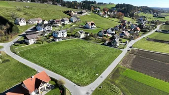 Luftaufnahme eines großen grünen Grundstücks, umgeben von Wohnhäusern und Straßen in ländlicher Umgebung.