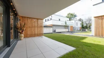 Moderne Terrasse mit Fliesenboden, Holzelementen und direktem Zugang zur Grünfläche.