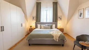 Helles Schlafzimmer mit Dachschrägen, großem Kleiderschrank und gemütlichem Bett.
