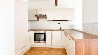 Helle Einbauküche mit U-förmiger Anordnung, Holzarbeitsplatten und sichtbaren Deckenbalken.